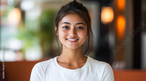 Young woman with a warm smile posing in a cozy indoor setting during daylight hours