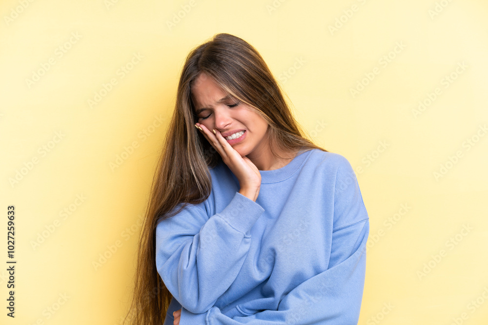 Young caucasian woman isolated on yellow background with toothache Young caucasian woman isolated on yellow background with toothache