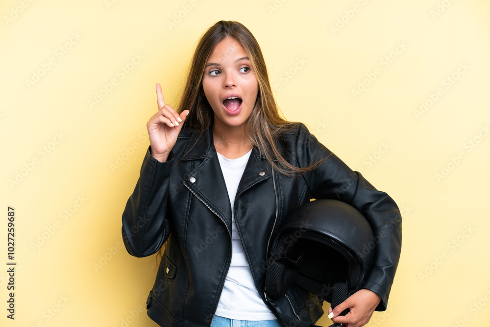 Young caucasian woman with a motorcycle helmet isolated on yellow background thinking an idea pointing the finger up Young caucasian woman with a motorcycle helmet isolated on yellow background thinking an idea pointing the finger up