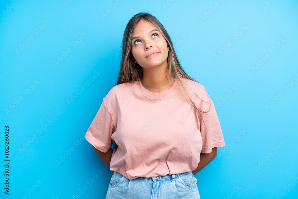Young caucasian woman isolated on blue background and looking up Young caucasian woman isolated on blue background and looking up