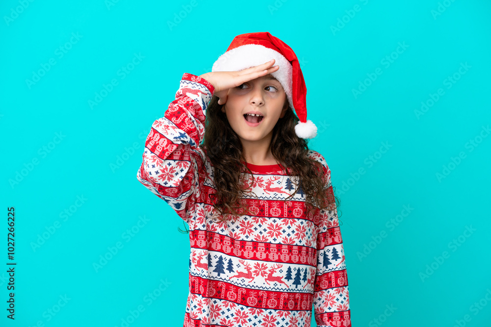 Little caucasian with christmas hat isolated on blue background with surprise and shocked facial expression Little caucasian with christmas hat isolated on blue background with surprise and shocked facial expression