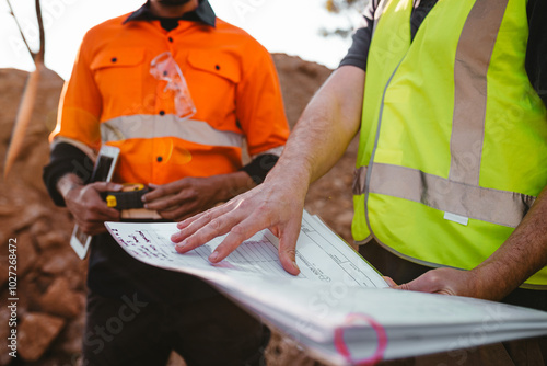 Builders holding a blueprint at the construction site photo