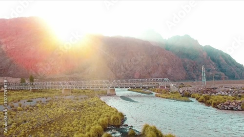 Aerial shot of a river sorrounded of mountains at sunset
