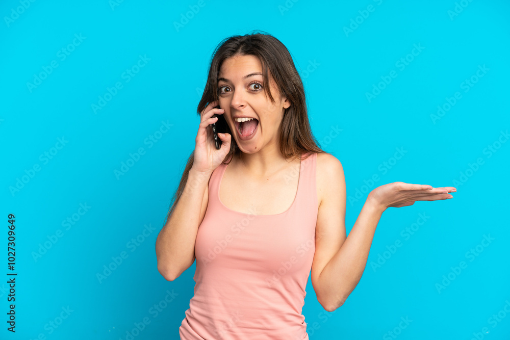 Young caucasian woman using mobile phone isolated on blue background with shocked facial expression Young caucasian woman using mobile phone isolated on blue background with shocked facial expression