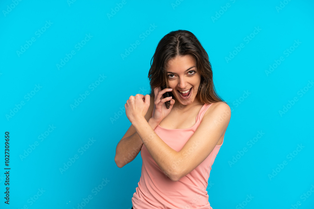 Fototapeta premium Young caucasian woman using mobile phone isolated on blue background celebrating a victory