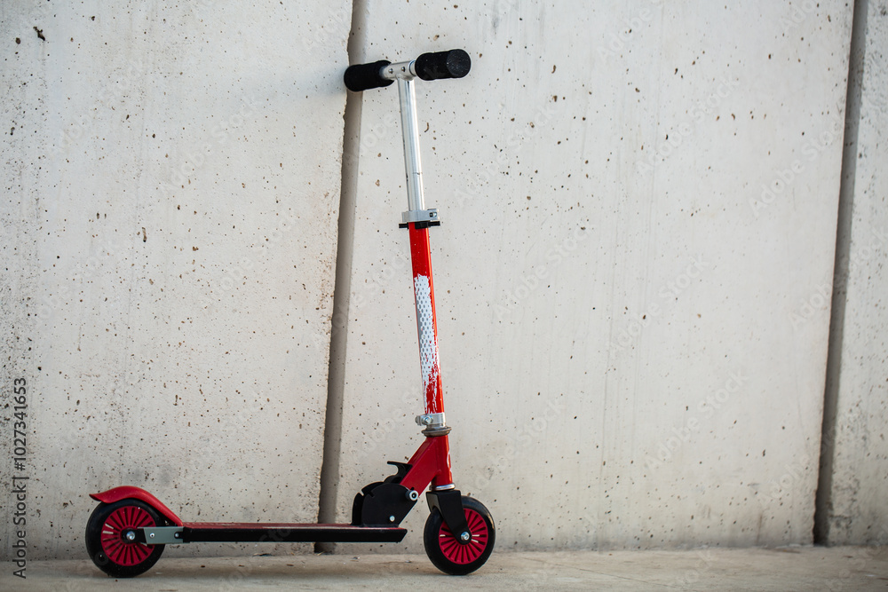 Children kick scooter parked near white wall