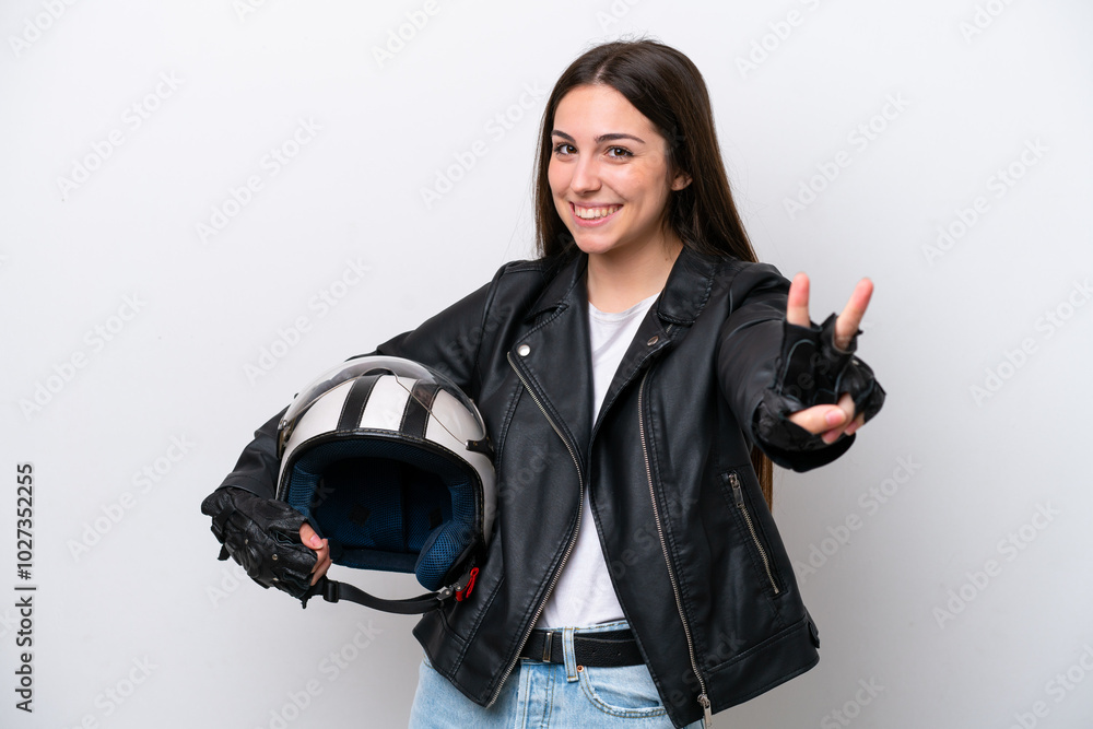 Young girl with a motorcycle helmet isolated on white background smiling and showing victory sign Young girl with a motorcycle helmet isolated on white background smiling and showing victory sign