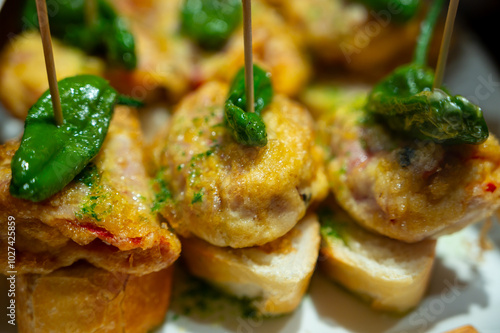 Typical snack of Basque Country, pinchos or pinxtos skewers with small pieces of bread, fish, sea food, sweet green pepper served in bar in San-Sebastian or Bilbao, Spain, close up photo