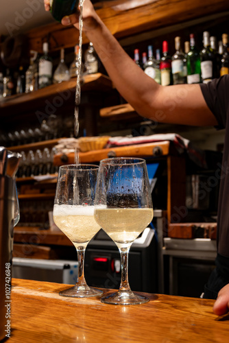 Pouring of txakoli or chacolí slightly sparkling very dry white wine produced in Spanish Basque Country in typical pinchos bar in old part of San Sebastian or Donostia, Spain photo