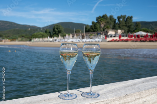 Summer time in Provence, two glasses of cold champagne cremant sparkling wine on famous Pampelonne sandy beach near Saint-Tropez in sunny day, Var department, France, beach club party photo