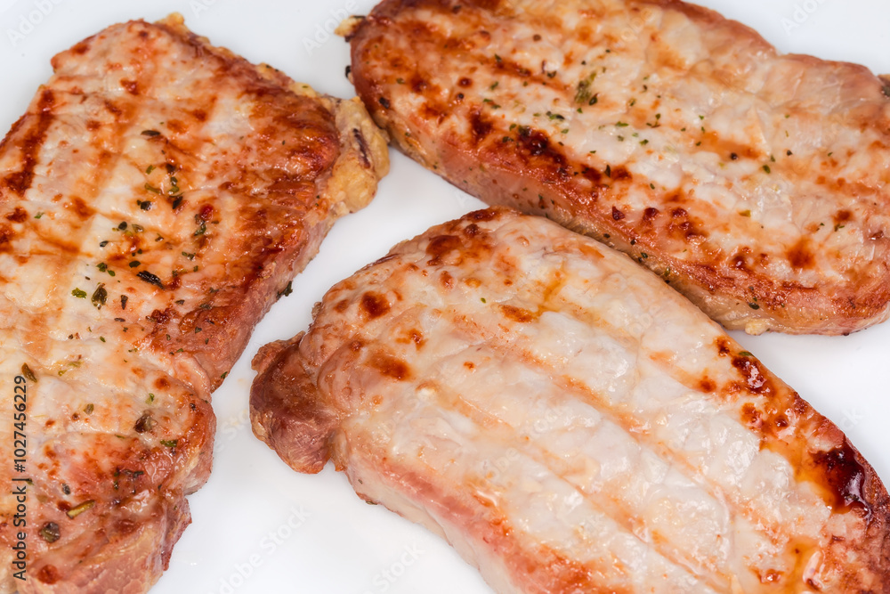 Grilled boneless pork chops with spices on dish, close-up Grilled boneless pork chops with spices on dish, close-up