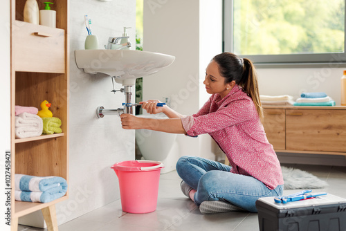 Konstfotografi Skilled woman repairing a leaky sink by herself