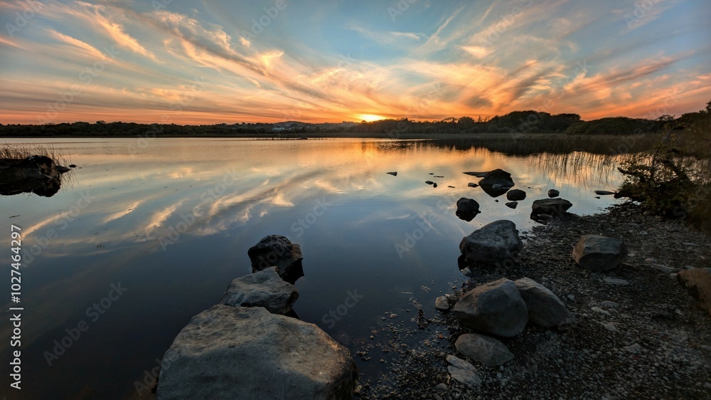 Beautiful orange sunset lakeside landscape scenery at Ballyquirke lough, Galway, Ireland, nature background