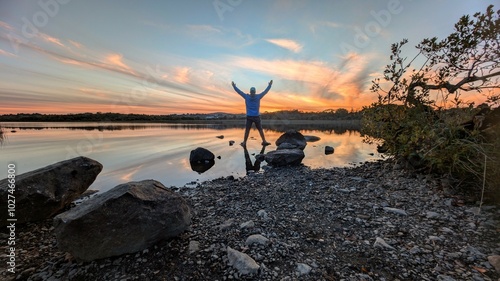 Obraz na płótnie Beautiful orange sunset lakeside landscape scenery, man reflected in water at Ballyquirke lough, Galway, Ireland, nature background w salonie