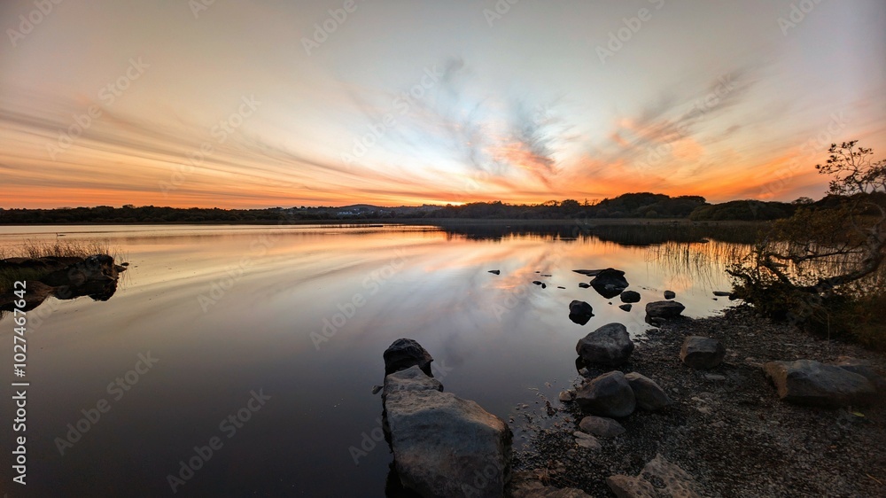 Beautiful orange sunset lakeside landscape scenery at Ballyquirke lough, Galway, Ireland, nature background