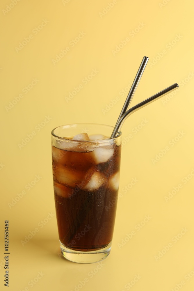 Tasty refreshing drink with straws in glass on beige background Tasty refreshing drink with straws in glass on beige background
