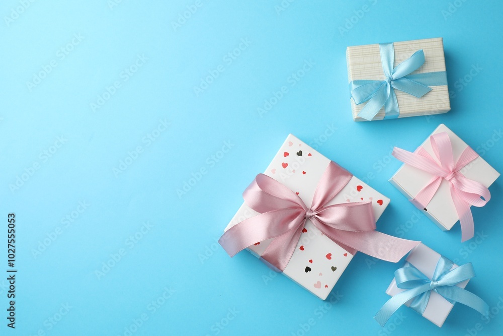 Gift boxes with bows on light blue background, flat lay. Space for text Gift boxes with bows on light blue background, flat lay. Space for text