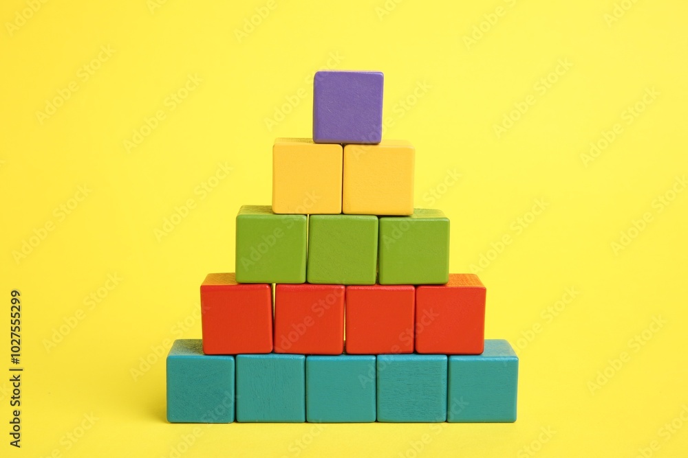 Pyramid of colorful cubes on yellow background Pyramid of colorful cubes on yellow background