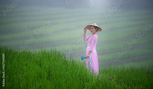 Beautiful women standing in a lush green tea field, likely in a rural area. They are wearing traditional conical hats and light-colored clothing with green tea platation background	 photo