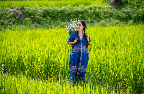 woman carries a large, woven basket on her back filled with white and purple flowers collected from the area nnection with nature, as well as the warmth of a beautiful, natural environment. photo