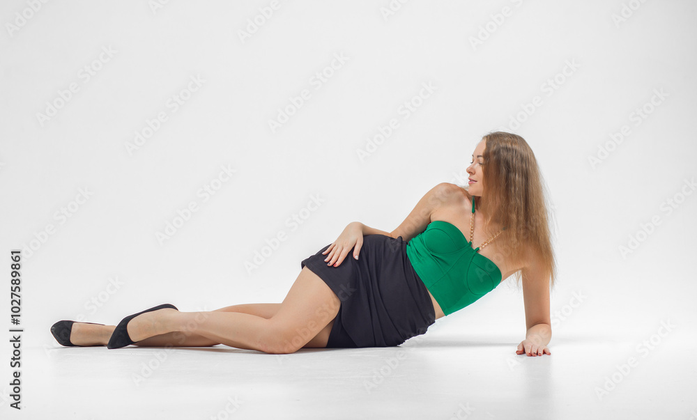 Woman in green top and black skirt posing in front of camera. She has long hair, she is standing on white background. Beautiful sexy body. Fitness and healthy eating concept. Woman in green top and black skirt posing in front of camera. She has long hair, she is standing on white background. Beautiful sexy body. Fitness and healthy eating concept.