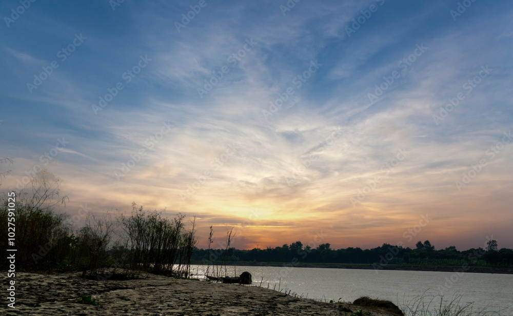 Gorai-Madhumati river of Bangladesh. Evening on the river. Fishing boats are tied on the river bank. The river flows under the twilight sky. Gorai-Madhumati river of Bangladesh. Evening on the river. Fishing boats are tied on the river bank. The river flows under the twilight sky.