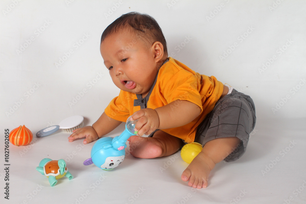 Adorable baby boy sitting and playing on white background Adorable baby boy sitting and playing on white background