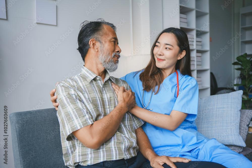 Fototapeta premium Young female doctor is comforting an elderly male patient while holding his hand at his home