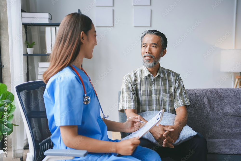 Obraz premium Young female doctor is holding a clipboard and talking to a senior male patient sitting on a sofa in the living room