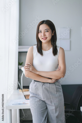 Portrait of smiling asian businesswoman standing with arms crossed looking at camera in office