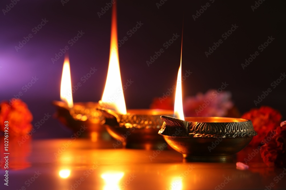 Diwali celebration. Diya lamps and beautiful flowers on color background, closeup Diwali celebration. Diya lamps and beautiful flowers on color background, closeup