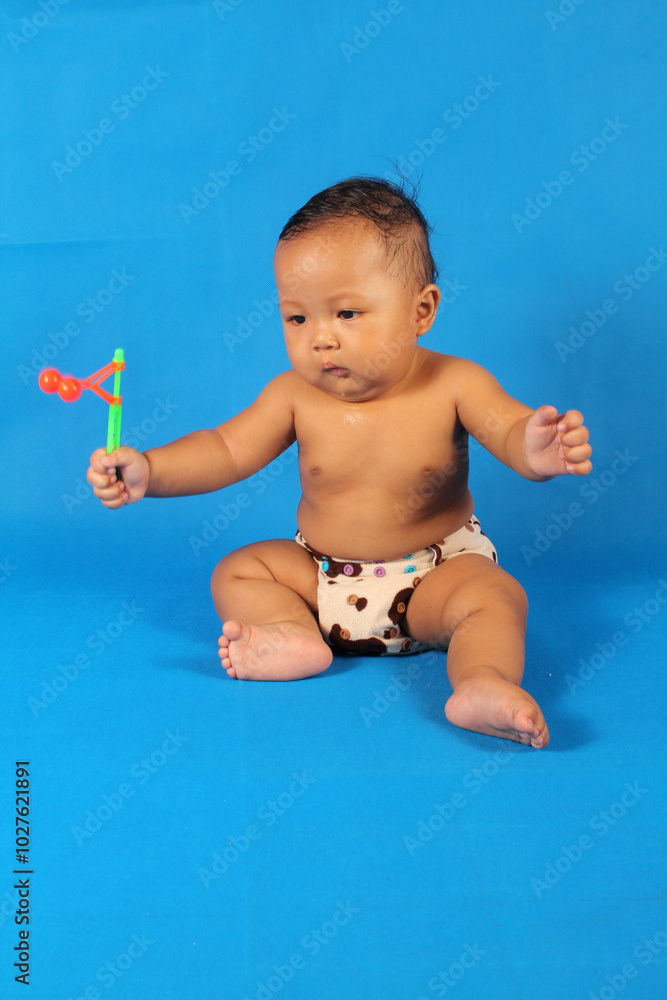 Adorable six month old fat baby boy takes off his shirt and pants wearing only a diaper