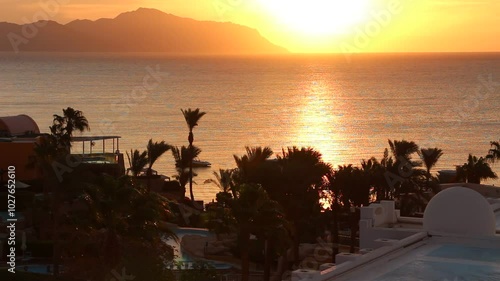 Dramatic morning sky with the sun rays crossing the clouds. Harmony of seclusion and meditation near the beautiful sea waves. The golden or blue hour of the sunrise or sunset. Hotel resort Egypt.	