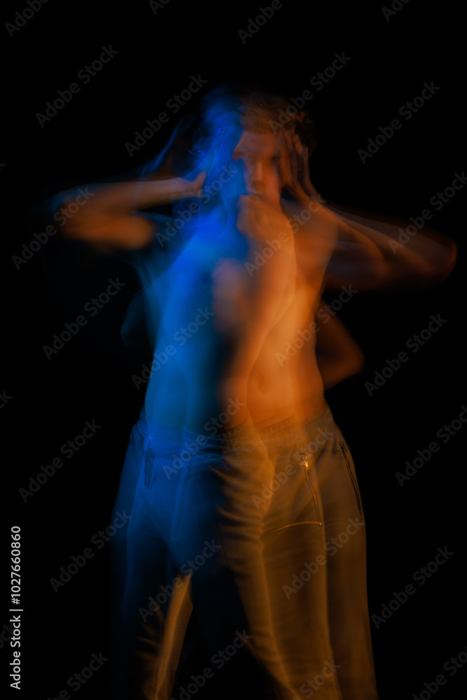 blurred silhouette, young man posing in the dark with red and blue light in the studio blurred silhouette, young man posing in the dark with red and blue light in the studio