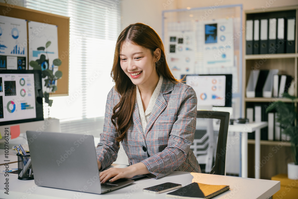 Asian businesswoman happily working on laptop in office, fully focused and dedicated to her tasks, showcasing professionalism and enthusiasm for work Asian businesswoman happily working on laptop in office, fully focused and dedicated to her tasks, showcasing professionalism and enthusiasm for work