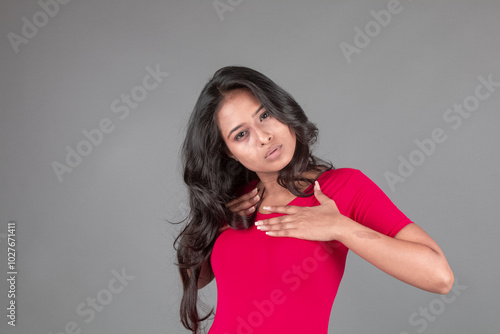 Healthy young woman in red t-shirt and black leggings doing yoga and stretching exercises with different facial expressions, isolated on grey background