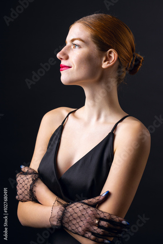 A young redhear girl with clean skin wearing black gloves. Beauty portrait of a woman on a black background in the studio. photo