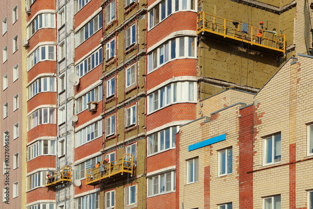Fototapeta premium Industrial mountaineering. High-altitude work. Repair and restoration of buildings, insulation of multi-story buildings..