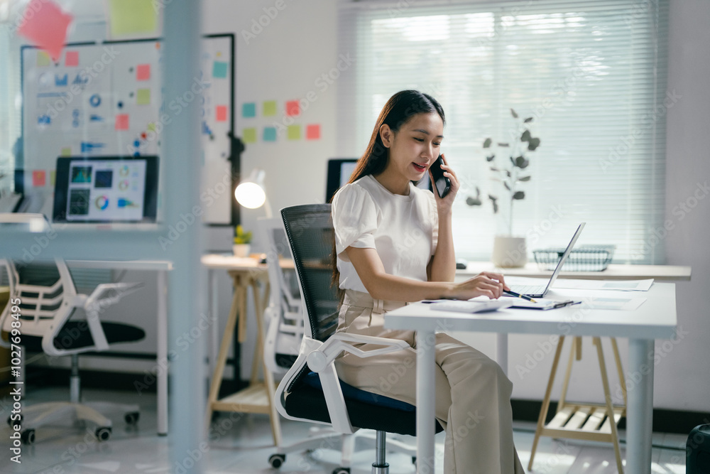 Confident businesswoman multitasks in a modern office, answering calls and taking notes with a smile, showcasing her tech-savvy approach to work Confident businesswoman multitasks in a modern office, answering calls and taking notes with a smile, showcasing her tech-savvy approach to work