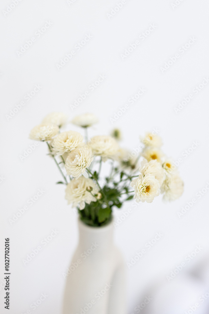 A simple vase of white flowers on a minimalist table against a soft, neutral backdrop in a serene indoor setting A simple vase of white flowers on a minimalist table against a soft, neutral backdrop in a serene indoor setting
