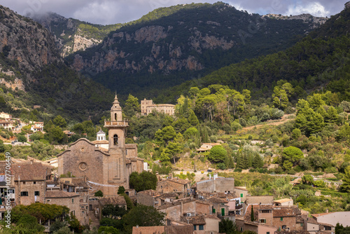 Panoramc view of the picturesque mountain village of Valldemossa with the old Iglesia de San Bartolomé surrounded by the stunning Tramuntana mountains in the background. photo