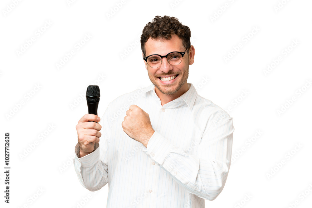 Brazilian man picking up a microphone over isolated chroma key background celebrating a victory Brazilian man picking up a microphone over isolated chroma key background celebrating a victory