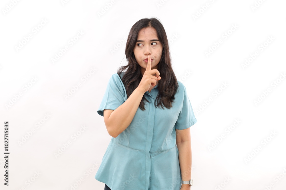 Mysterious Asian woman makes silence gesture shares secret looks aside isolated on white background. Hush be quiet Mysterious Asian woman makes silence gesture shares secret looks aside isolated on white background. Hush be quiet