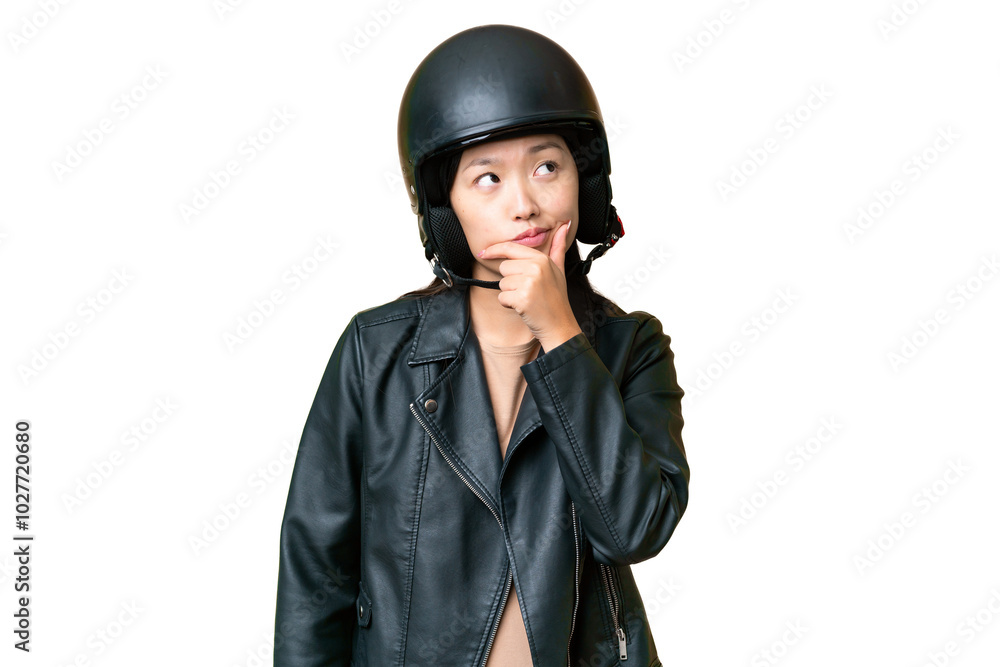 Young Asian woman with a motorcycle helmet over isolated chroma key background having doubts and with confuse face expression Young Asian woman with a motorcycle helmet over isolated chroma key background having doubts and with confuse face expression