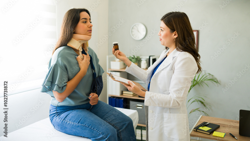 Doctor discusses medication-based treatment with her injured patient who is wearing a cervical collar and sling Doctor discusses medication-based treatment with her injured patient who is wearing a cervical collar and sling
