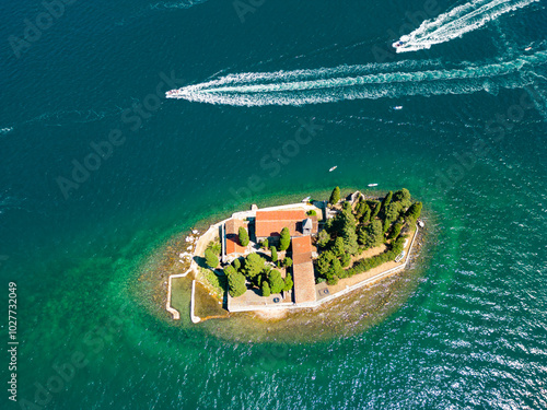 Aerial drone view of Sveti Dorde Island - Saint George Monastry in the middle of the island. In background is Perast city. Famous travel destination in Montenegro. Boats passing photo