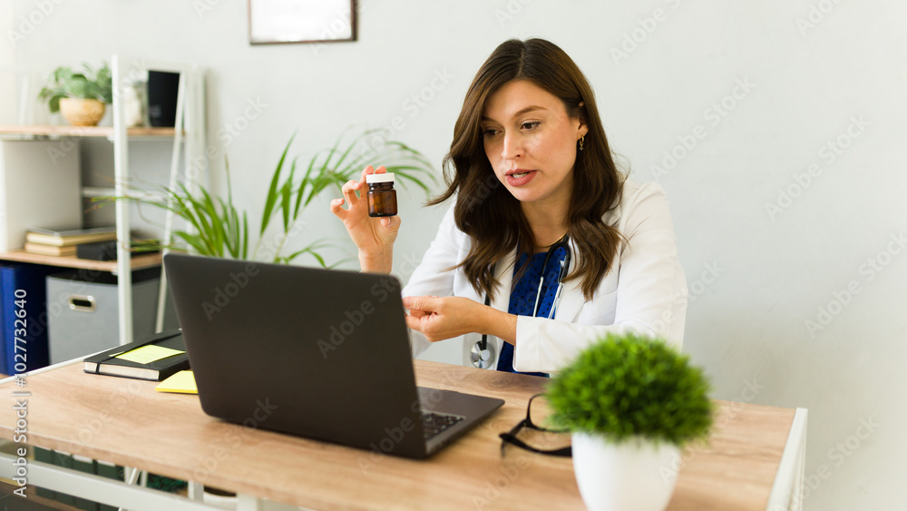 Doctor confidently explaining treatment to patient during video call consultation while holding bottle of pills Doctor confidently explaining treatment to patient during video call consultation while holding bottle of pills