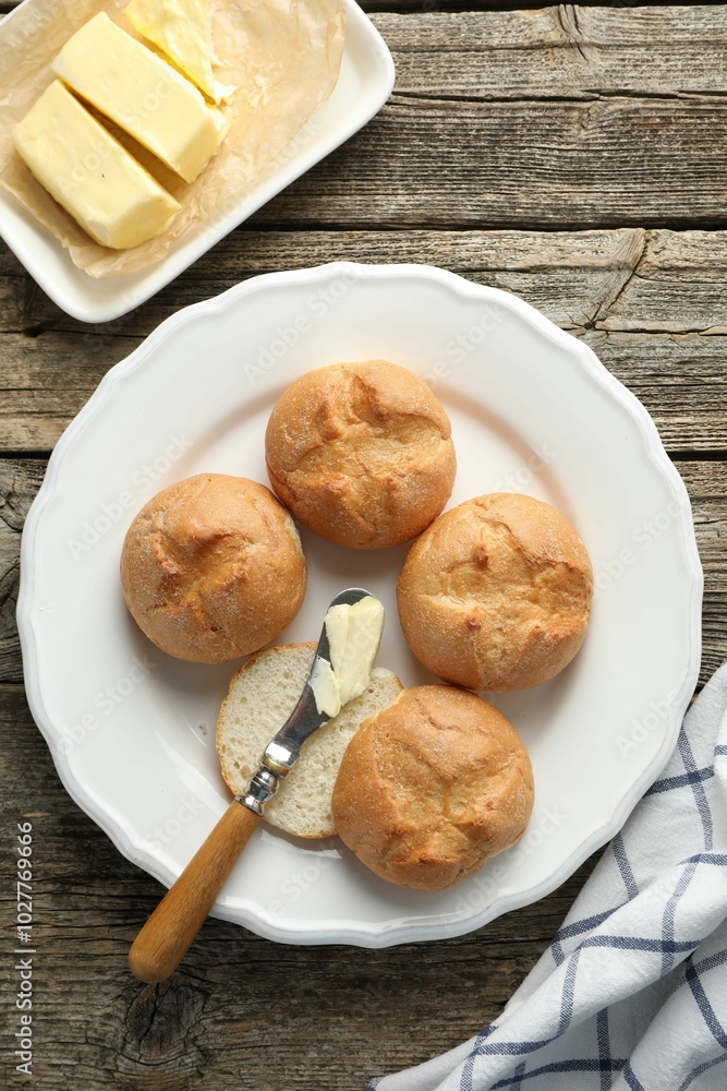 Plate with homemade tasty buns, butter and knife on wooden table, flat lay Plate with homemade tasty buns, butter and knife on wooden table, flat lay