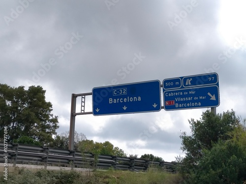 blue highway sign with the direction name Barcelona on a cloudy day