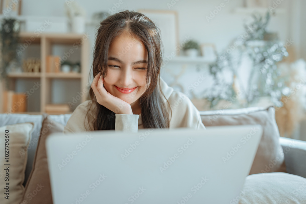 Fototapeta premium Happy young asian woman chatting on laptop with working, Beautiful female using notebook computer technology doing online job or browsing web while sitting at home.